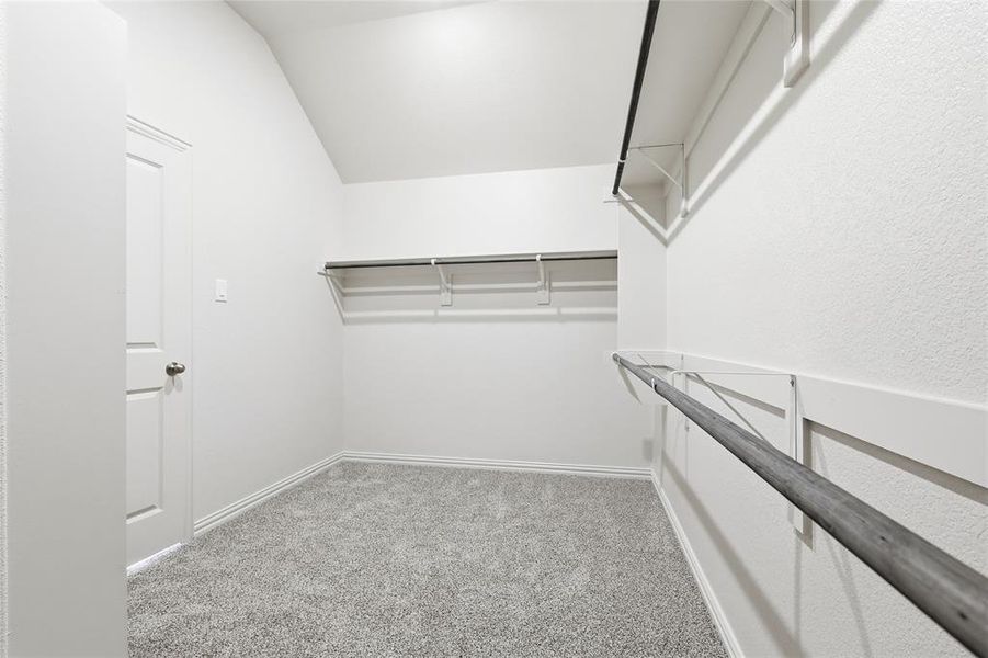 Spacious closet featuring light colored carpet and lofted ceiling Spacious closet featuring light colored carpet and lofted ceiling