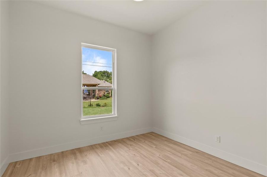 Empty room featuring plenty of natural light, baseboards, and wood finished floors Empty room featuring plenty of natural light, baseboards, and wood finished floors
