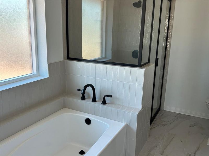 Bathroom with a garden tub, a shower stall, and marble finish floors
