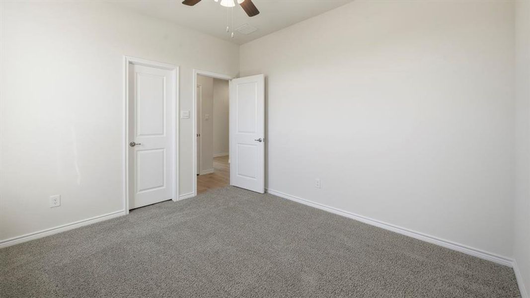 Carpeted empty room with ceiling fan and baseboards