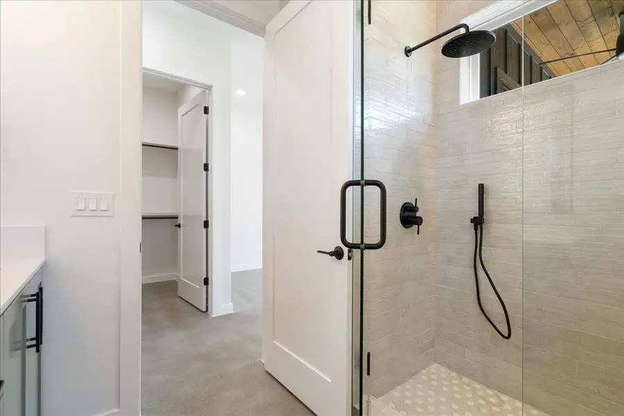 Full bath featuring a shower stall, vanity, and a spacious closet
