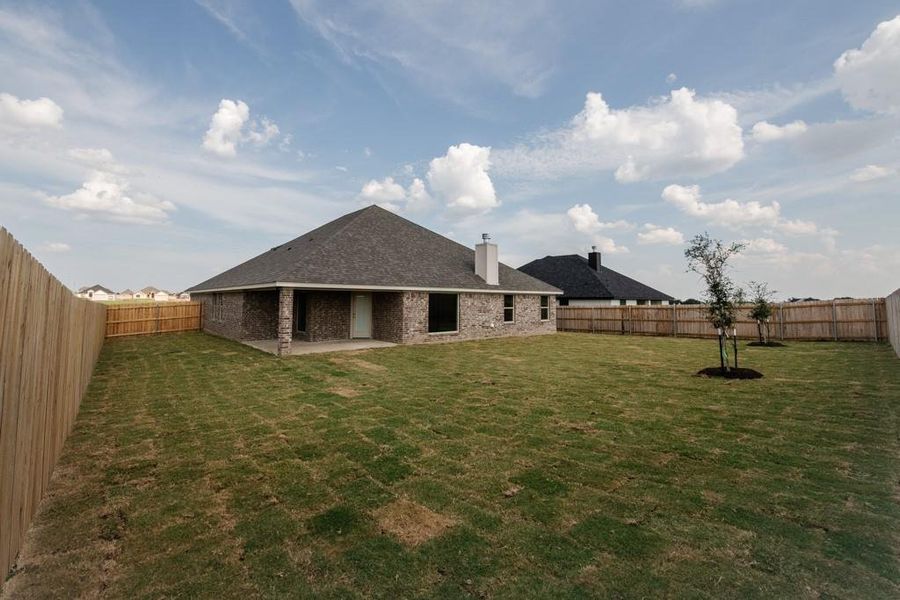 Rear view of house with a fenced backyard, a patio, a chimney, brick siding, and a shingled roof Rear view of house with a fenced backyard, a patio, a chimney, brick siding, and a shingled roof