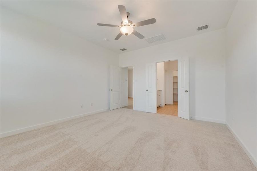 Unfurnished bedroom with light carpet, a closet, ceiling fan, and a walk in closet