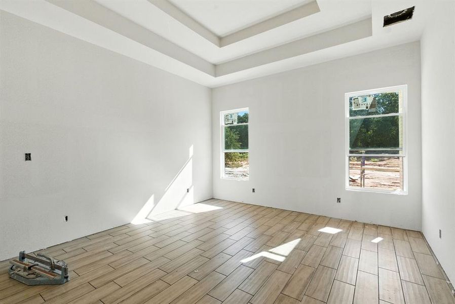 Unfurnished room featuring wood finish floors and a raised ceiling Unfurnished room featuring wood finish floors and a raised ceiling