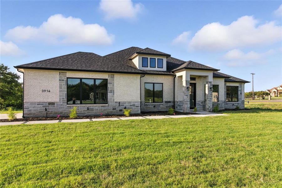 Prairie-style house featuring brick siding, a front yard, and a shingled roof