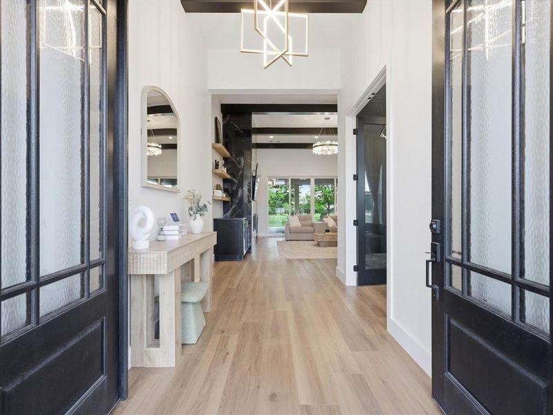 Entryway featuring paneled doors with obscure glass, wood-finish flooring, and a modern chandelier