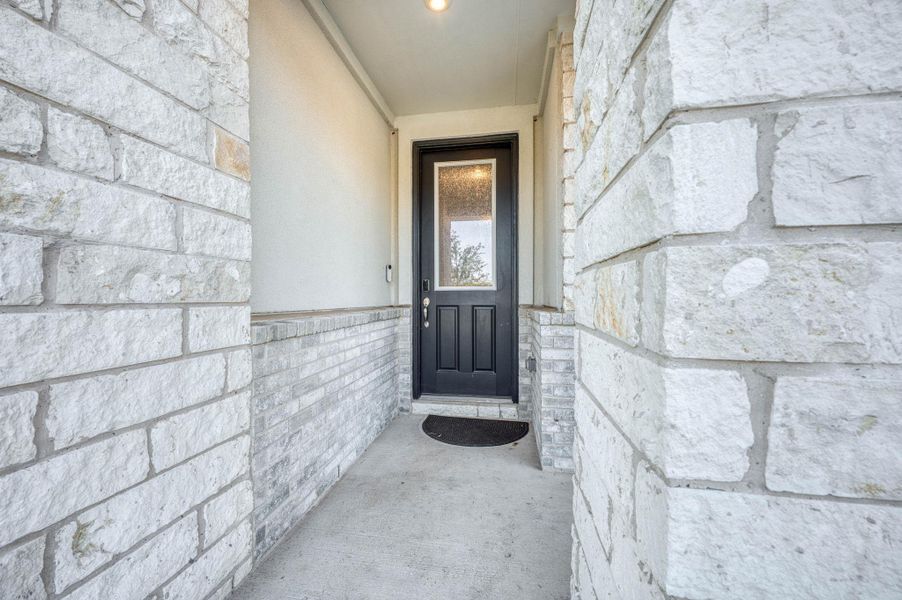 Textured light stone masonry framing a recessed entryway with a solid concrete floor. Textured light stone masonry framing a recessed entryway with a solid concrete floor.