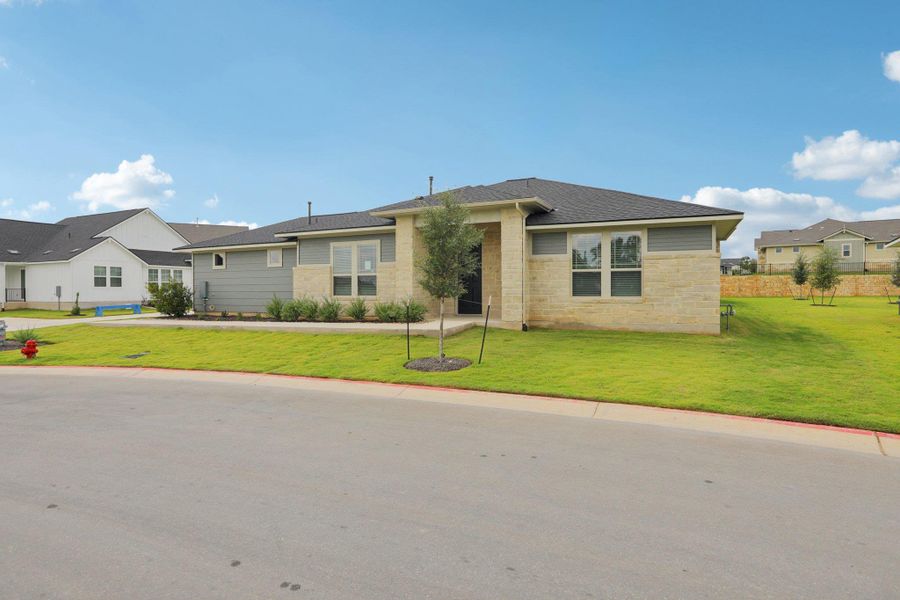 View of front of home featuring a front yard, roof with shingles, a residential view, and stone siding