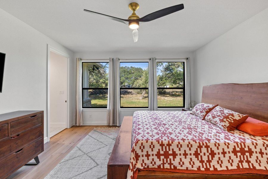 Bedroom featuring light wood-type flooring, multiple windows, and a ceiling fan