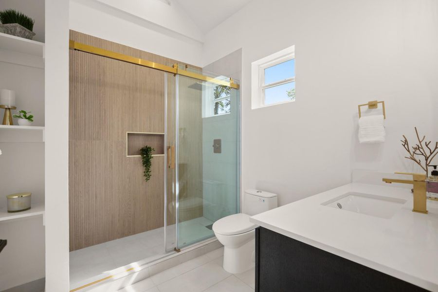 Full bath with vanity, a stall shower, lofted ceiling, and light tile patterned flooring