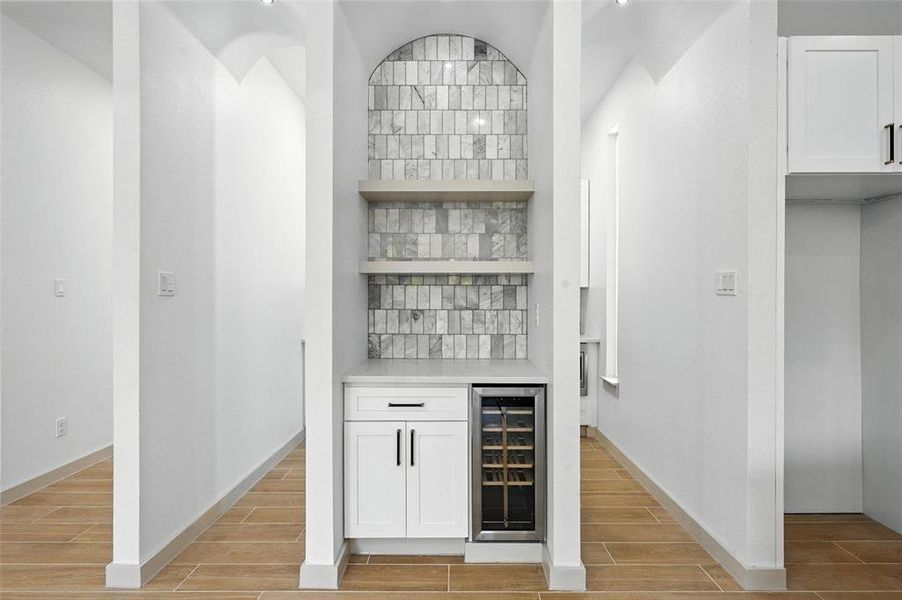Indoor dry bar featuring beverage cooler, wood tiled floors, and tasteful backsplash Indoor dry bar featuring beverage cooler, wood tiled floors, and tasteful backsplash