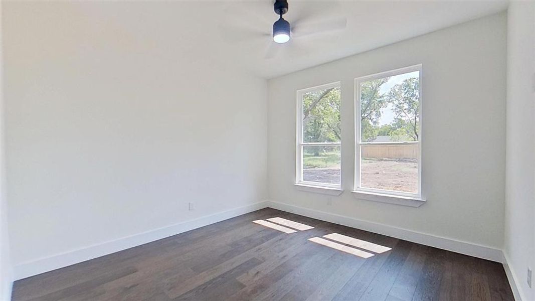 Spare room with dark wood-type flooring and a ceiling fan