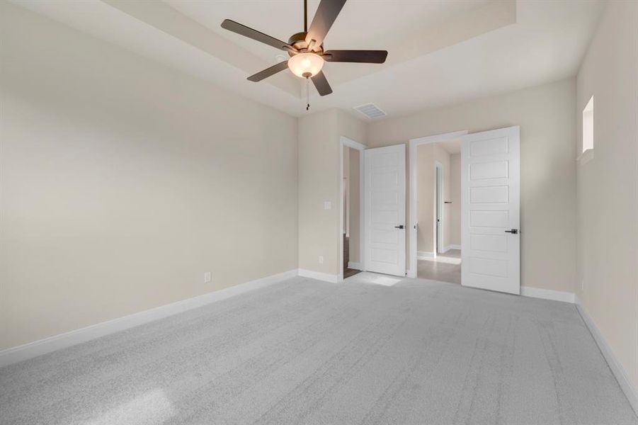 Unfurnished bedroom featuring carpet, a ceiling fan, and a raised ceiling