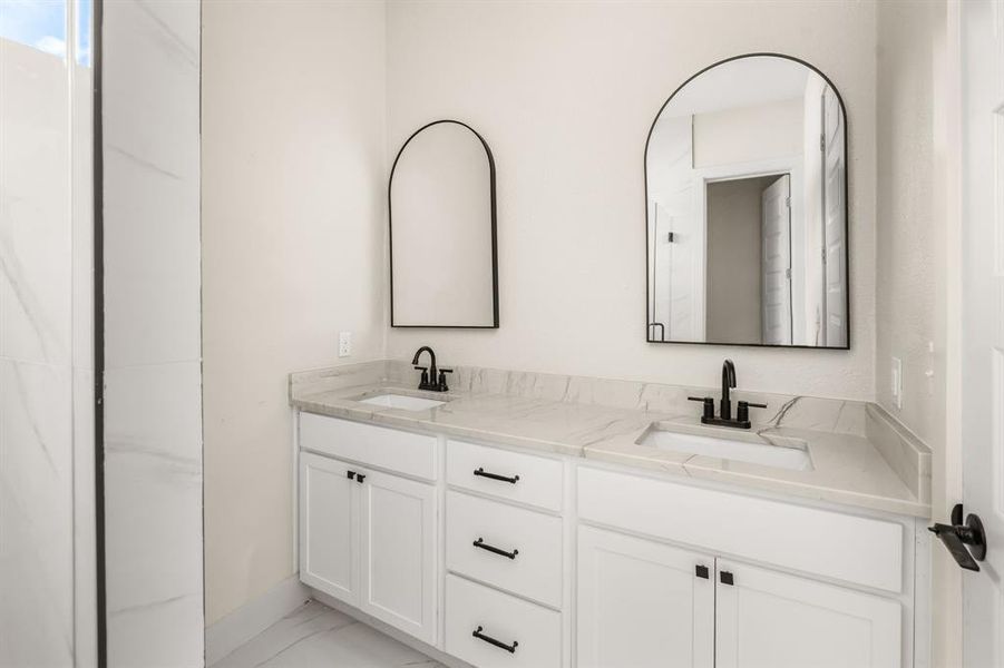 Full bathroom featuring double vanity and light marble finish flooring