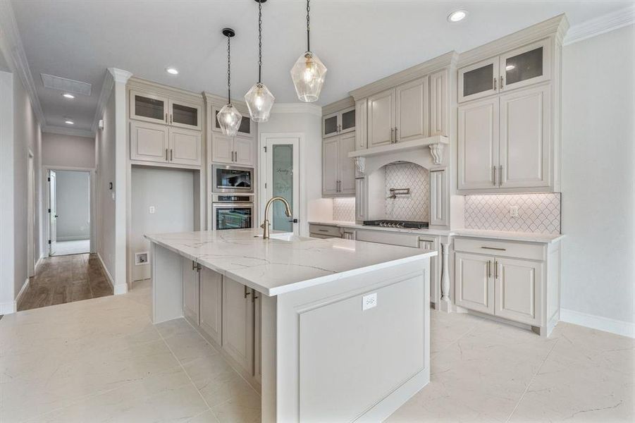 Kitchen featuring ornamental molding, stainless steel appliances, a sink, a kitchen island with sink, and tasteful backsplash