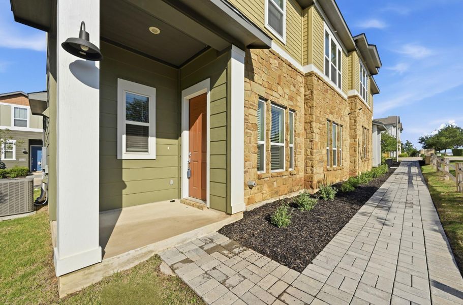 Exterior featuring a stone and siding facade, a covered entry porch, a paver walkway, mature landscaping, and a fenced perimeter Exterior featuring a stone and siding facade, a covered entry porch, a paver walkway, mature landscaping, and a fenced perimeter