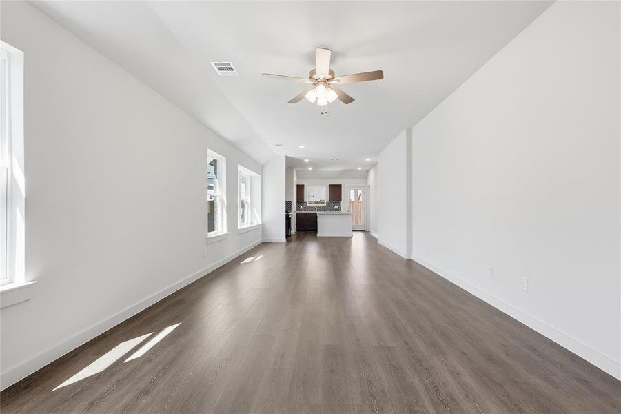 Unfurnished living room featuring ceiling fan and dark wood-style flooring