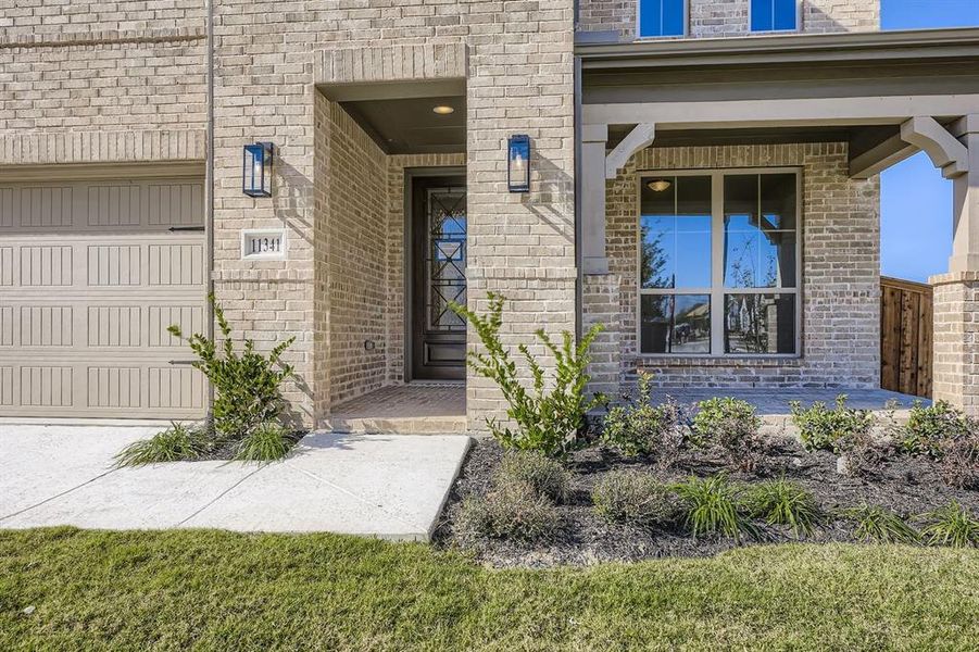 View of exterior entry with brick siding and a garage