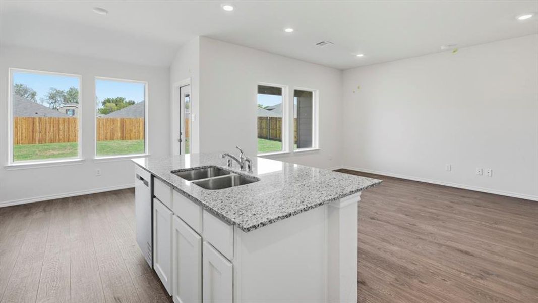 Kitchen featuring white cabinets, a kitchen island with sink, light stone counters, light wood-style flooring, and open floor plan Kitchen featuring white cabinets, a kitchen island with sink, light stone counters, light wood-style flooring, and open floor plan