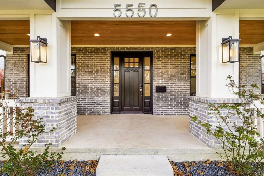 View of exterior entry with a porch and brick siding