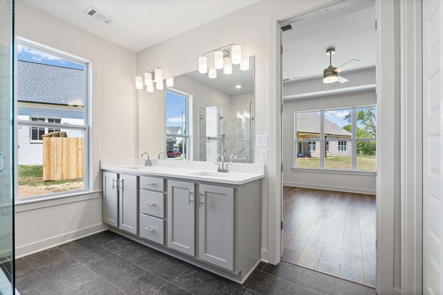 Bathroom with double vanity, a stall shower, and a ceiling fan