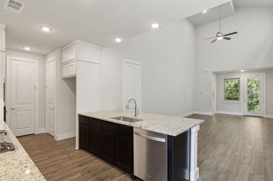 Kitchen with open floor plan, a sink, stainless steel dishwasher, and wood finished floors