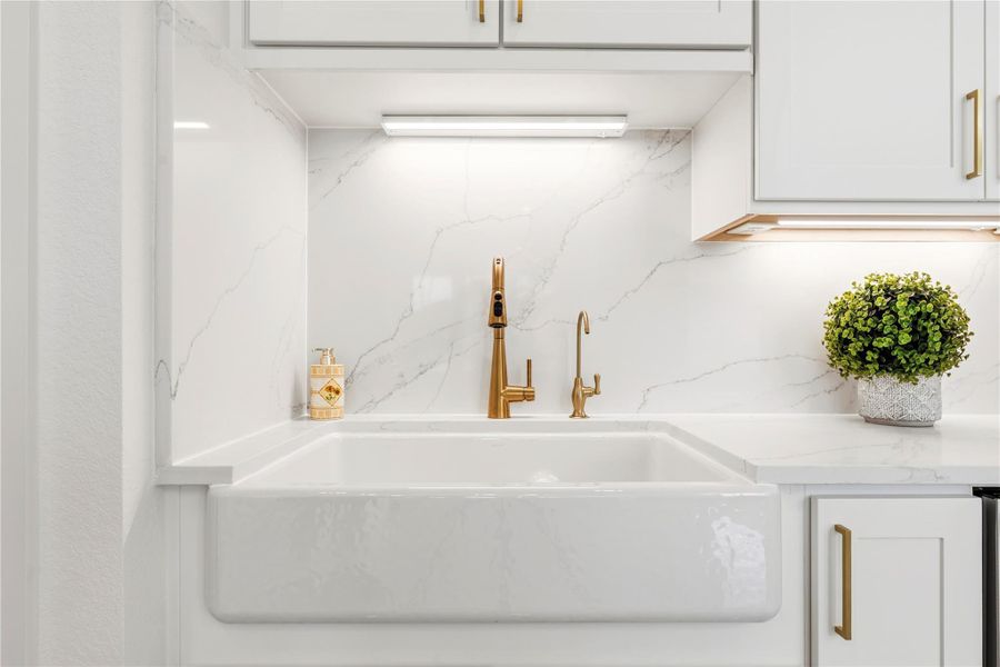 The refined kitchen aesthetic is completed by a deep farmhouse sink, premium gold-tone fixtures, and custom soft-closing cabinetry, offering a sophisticated and luxurious touch to daily tasks.