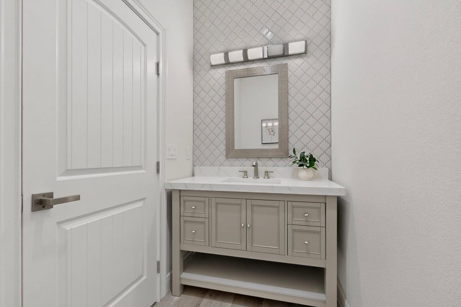 An elegant vanity stands against a patterned tile backsplash in this modern powder room.
