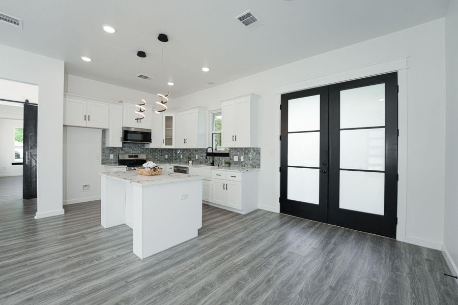 Kitchen with a barn door, french doors, visible vents, and appliances with stainless steel finishes