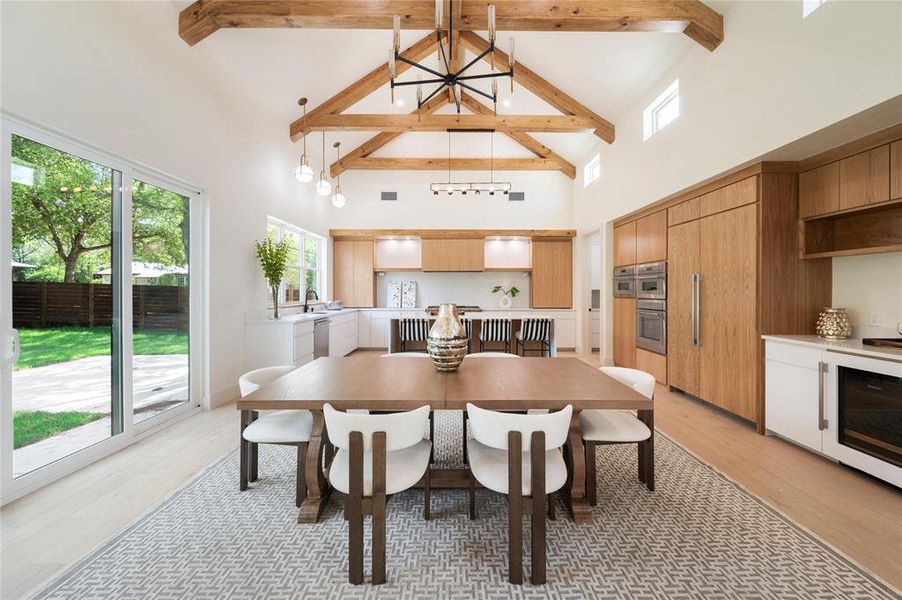 Dining area featuring light hardwood / wood-style floors, beamed ceiling, high vaulted ceiling, and a chandelier