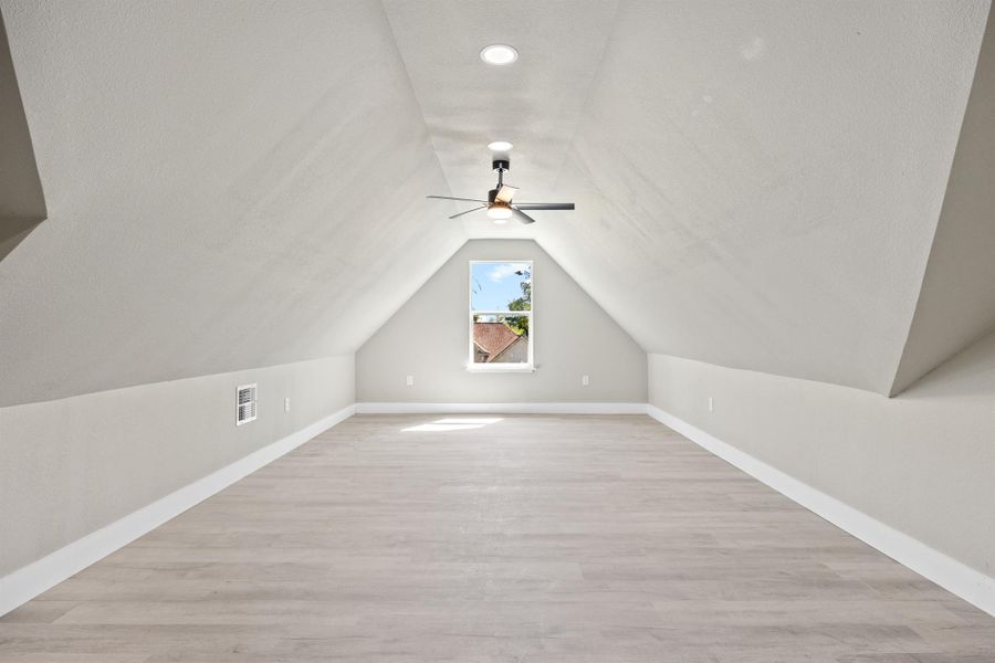 Additional living space with a ceiling fan, visible vents, lofted ceiling, light wood finished floors, and baseboards Additional living space with a ceiling fan, visible vents, lofted ceiling, light wood finished floors, and baseboards