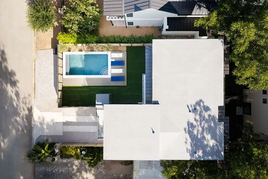 An aerial perspective showcases the modern roofline and a backyard pool with surrounding turf grass. An aerial perspective showcases the modern roofline and a backyard pool with surrounding turf grass.