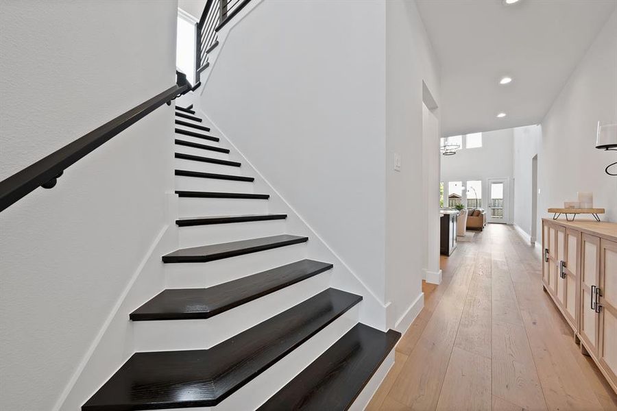 Staircase featuring dark wood-finish treads, white risers, and a contemporary black metal railing Staircase featuring dark wood-finish treads, white risers, and a contemporary black metal railing