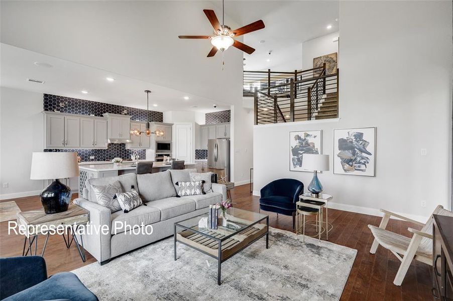 Living room featuring a towering ceiling, wood-type flooring, and ceiling fan