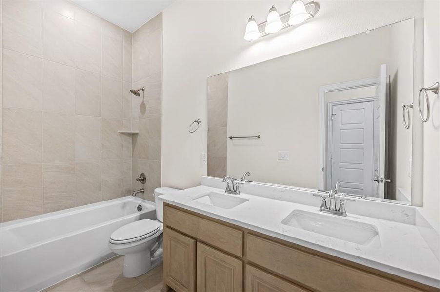 Full bath featuring double vanity, shower / bath combination, and light tile patterned floors Full bath featuring double vanity, shower / bath combination, and light tile patterned floors