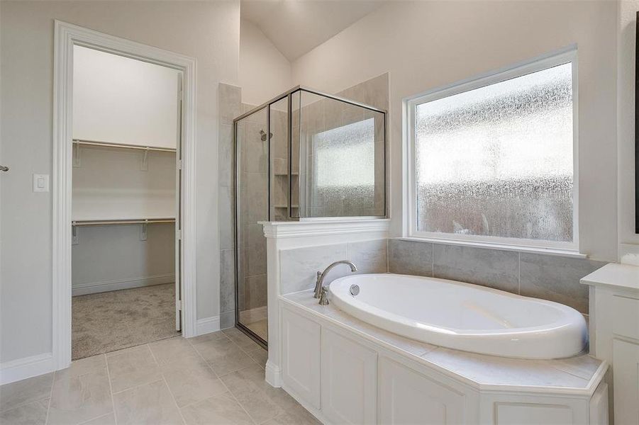 Bathroom featuring tile patterned floors, separate shower and tub, and vaulted ceiling