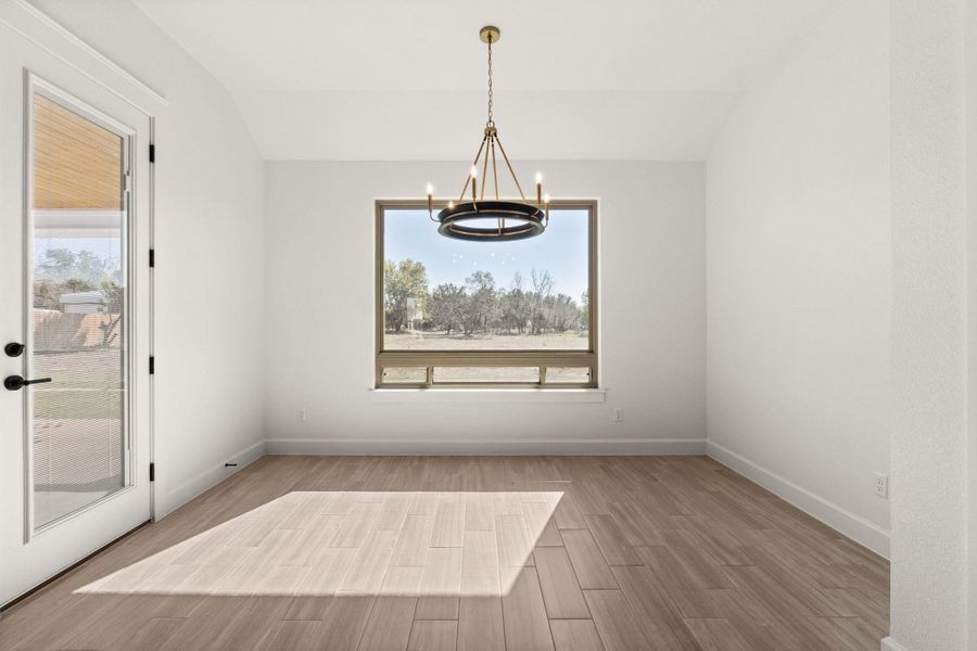 Unfurnished dining area with light wood-style flooring, a chandelier, and lofted ceiling