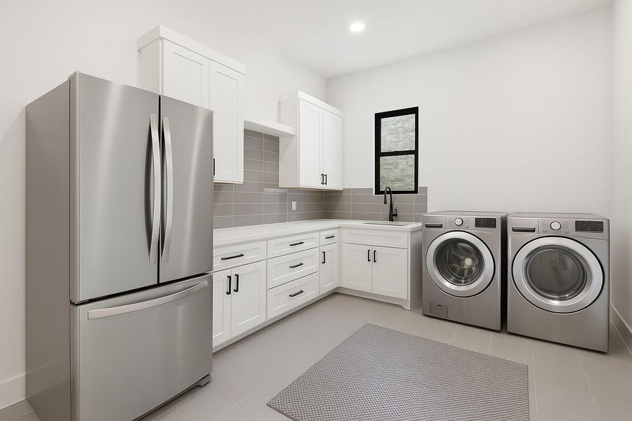 The in home laundry room stretches off the mud room entry and comes with ample storage cabinetry, a vanity, sink, and space for a second fridge.