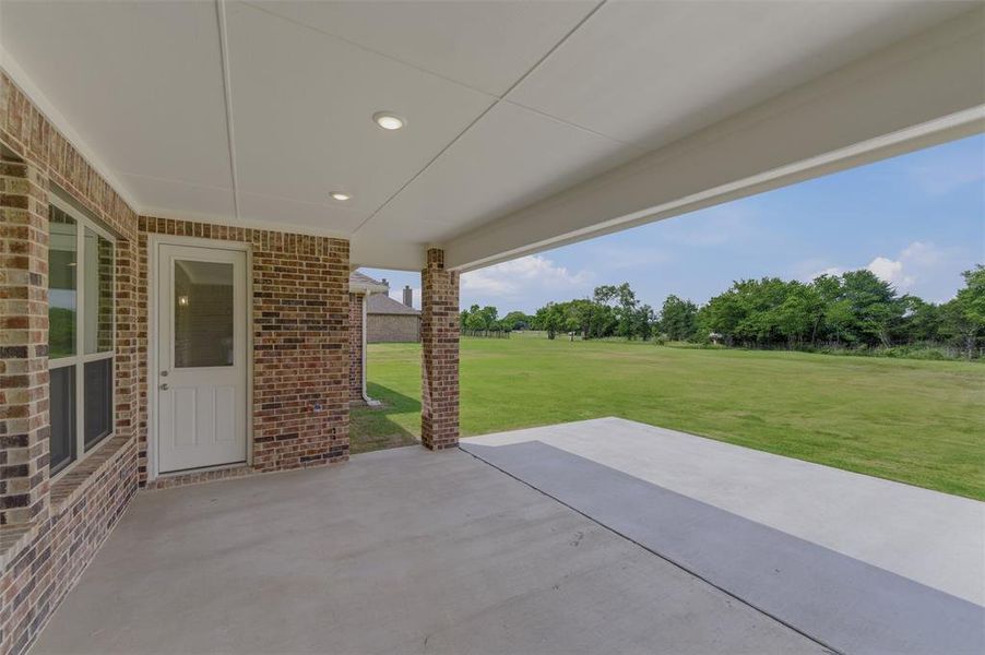 Expansive covered patio featuring a concrete surface, brick columns, and recessed lighting Expansive covered patio featuring a concrete surface, brick columns, and recessed lighting