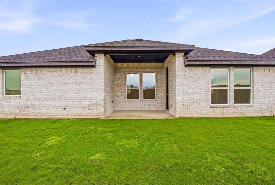 The property features a well-maintained lawn and a covered patio area