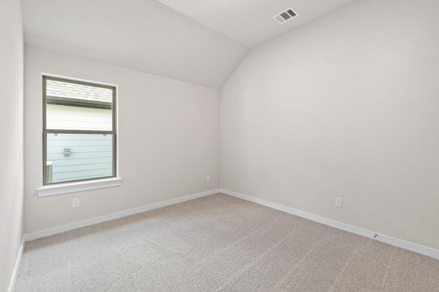 A quiet bedroom with a vaulted ceiling and light-colored carpeting offers a serene personal retreat.