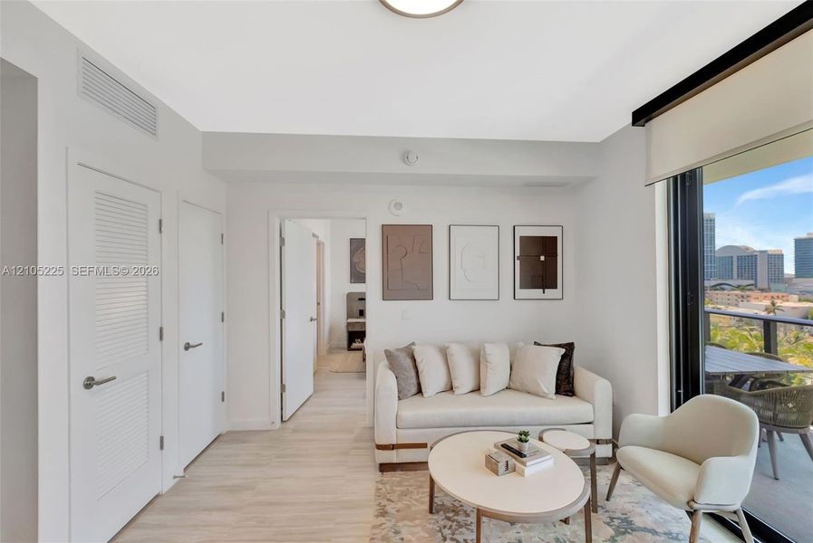 Light wood-finish flooring, recessed ceiling lighting, a louvered door, a full-height glass sliding door, and a private balcony with city scenery