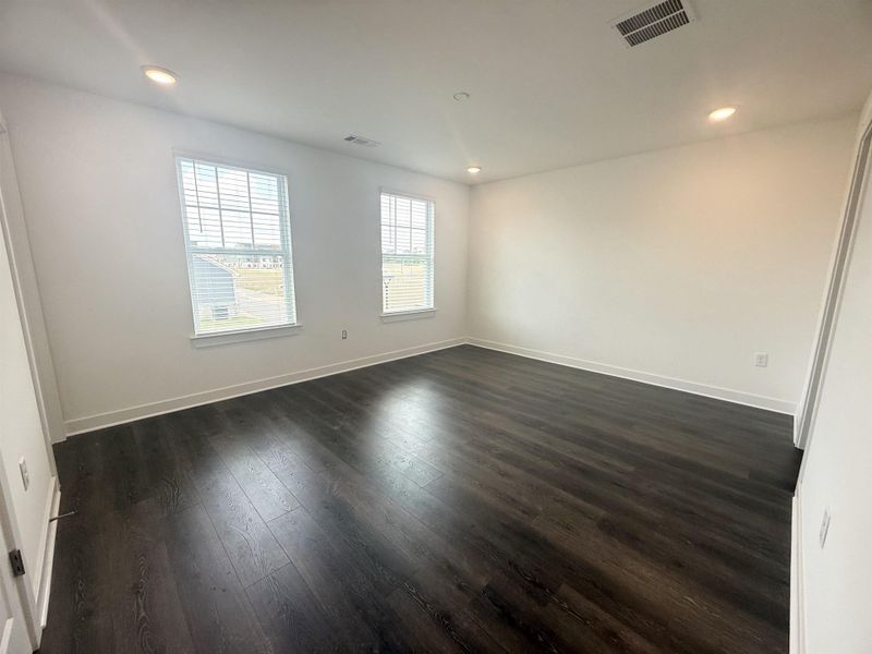 Spacious room featuring dark wood-finish flooring, recessed lighting, and white baseboards