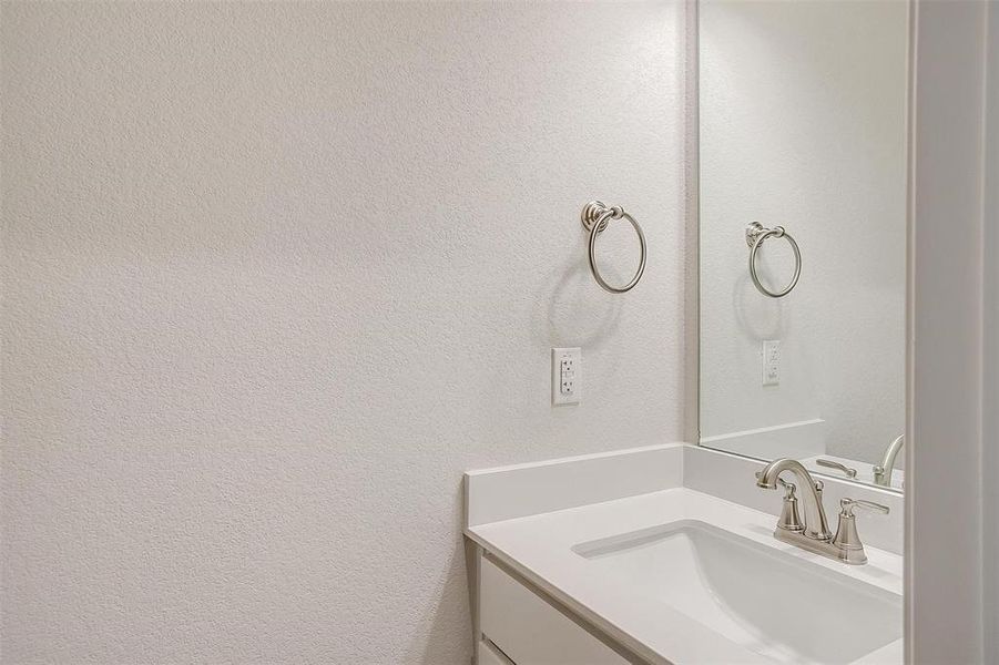 Bathroom featuring a textured wall and vanity