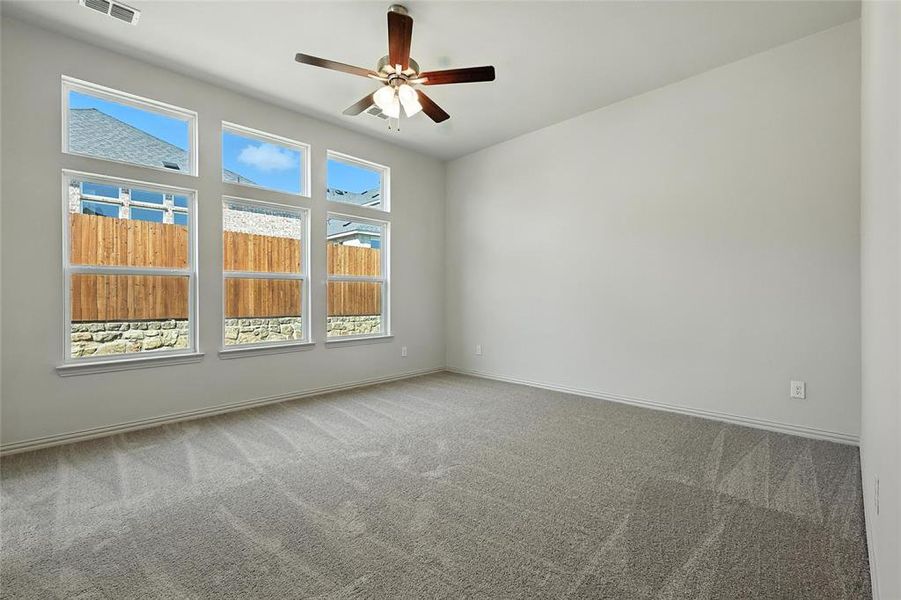 Carpeted empty room with ceiling fan and baseboards Carpeted empty room with ceiling fan and baseboards