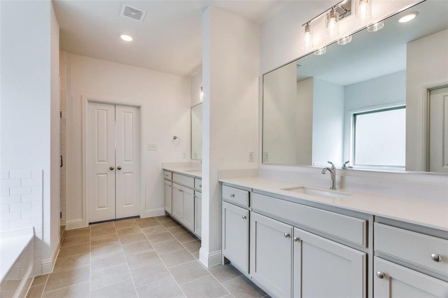 Bathroom with vanity, a relaxing tiled tub, and tile patterned flooring