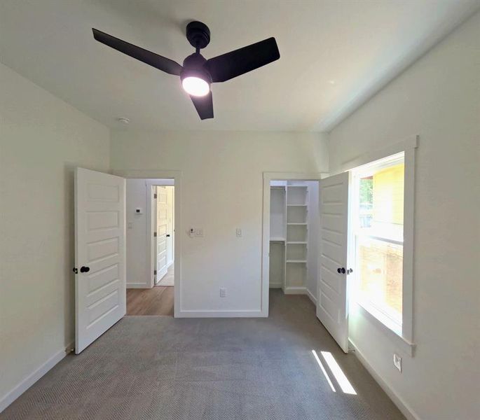 Unfurnished bedroom featuring a walk in closet, carpet flooring, and a ceiling fan Unfurnished bedroom featuring a walk in closet, carpet flooring, and a ceiling fan