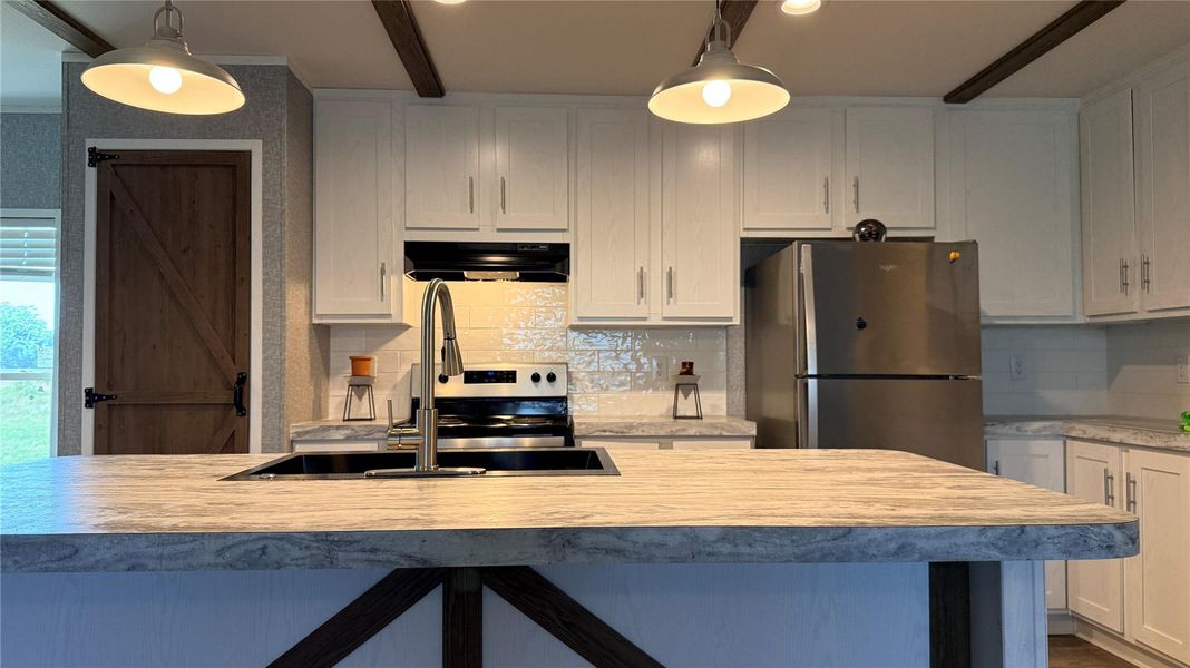 A contemporary kitchen features bright cabinetry, stainless steel appliances, and a central island with an integrated sink. A contemporary kitchen features bright cabinetry, stainless steel appliances, and a central island with an integrated sink.