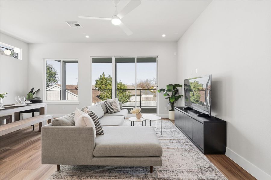 Natural light floods the living area through oversized sliding doors and a picture window, creating a seamless connection to the covered outdoor space just beyond, an easy extension of how the home lives day to day.