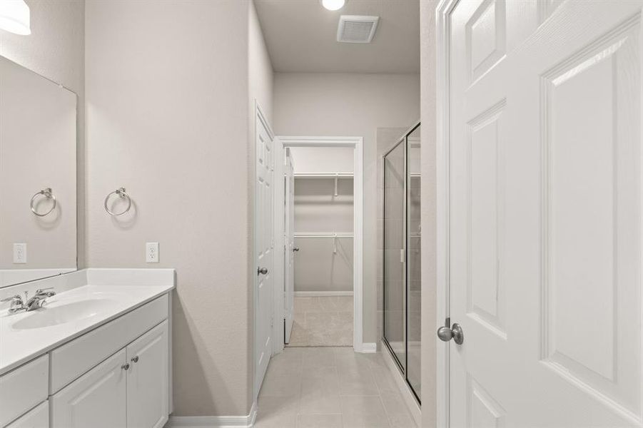 This additional view of your primary bathroom features tile flooring, fresh paint, walk-in shower, and a large walk-in closet.